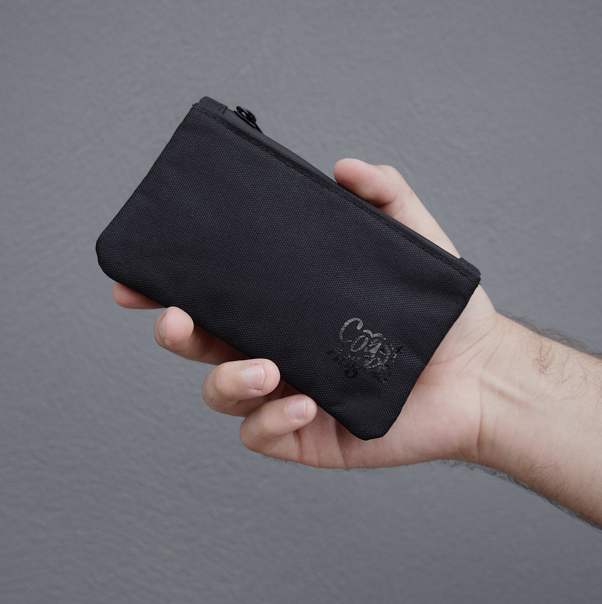 Hand holding the Coast Angels Camden Smell Proof Pouch