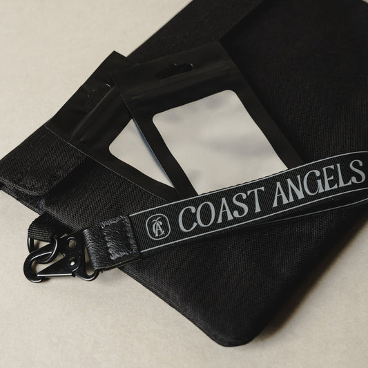 Black bag with Coast Angels strap on a beige background